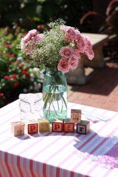 a vase filled with pink flowers sitting on top of a table next to wooden blocks