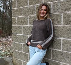 a woman leaning against a brick wall with her feet on the ground and smiling at the camera