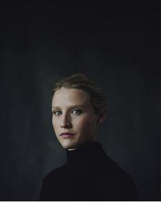 a woman with blonde hair wearing a black turtle neck sweater and looking at the camera