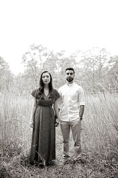 a man and woman standing next to each other in tall grass