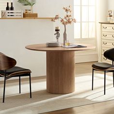 a dining table with two chairs and a vase on it in a living room next to a dresser