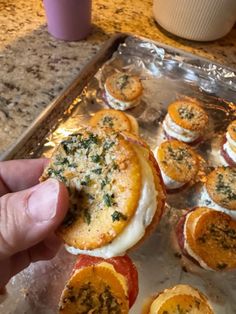 someone is holding an egg and cheese sandwich in front of other food items on a baking sheet