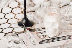 a candle is sitting on top of a book next to a glass jar with a skull in it