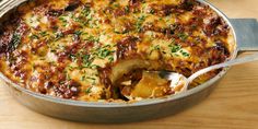 a casserole dish is shown with a serving spoon in it and garnished with fresh herbs