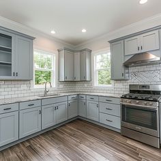 a kitchen with gray cabinets and wood floors