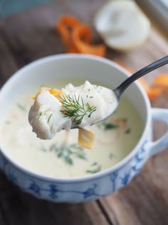 a spoon full of soup with dumplings in it and carrots on the side