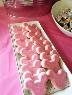 pink and white cookies in the shape of hearts are on a table next to a bowl of candy