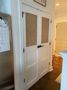 a kitchen with a stainless steel refrigerator freezer and wooden flooring next to a white wall