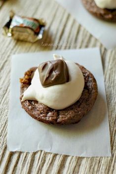 a chocolate cookie with white icing on top sitting on a piece of parchment paper