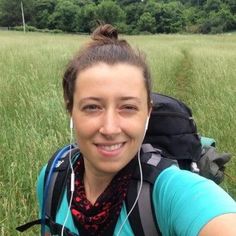 a woman is taking a selfie in the grass with her backpack and headphones on