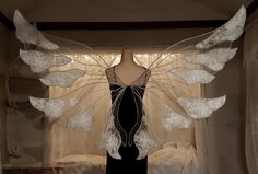 a mannequin with white wings in front of a window