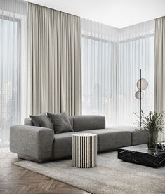 a living room filled with furniture and large windows covered in sheer drapes,