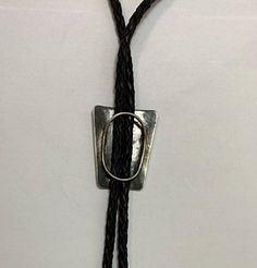 Beautiful Navajo handmade sterling silver Lowell Draper attributed bolo tie has braided black leather straps with handmade sterling silver tips. The center piece has a diagonally slanting linear design. Condition: Excellent! No damage or wear Artist: Unsigned Weight: 27 grams Measurements: 19 inches long (38 inches without the clip) Center piece is 1 3/4 inches tall x 1 1/2 inches wide Tips are 2 1/2 inches long Handmade Adjustable Lariat Bolo Ties, Silver Bohemian Bolo Tie With Adjustable Cord, Black Engraved Western Jewelry, Artisan Adjustable Lariat Bolo Tie, Adjustable Sterling Silver Bolo Tie For Gifts, Silver Lariat Bolo Tie With Adjustable Cord, Black Western Bolo Tie With Adjustable Length, Western Black Bolo Tie With Adjustable Length, Western Style Black Bolo Tie With Adjustable Length