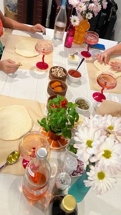 several people sitting at a table making pizzas and condiments for each other