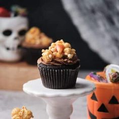 a cupcake with chocolate frosting and sprinkles on top, sitting on a pedestal