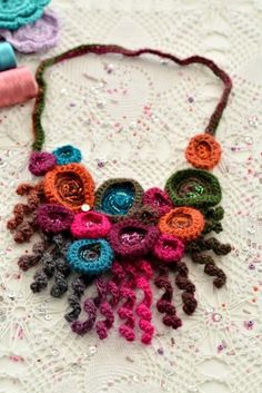 a crocheted necklace with flowers and beads on top of a lace doily