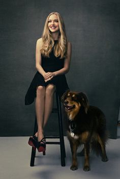 a black and white photo of a woman sitting on a chair next to a dog