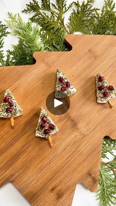 three pieces of food are placed on a cutting board next to some fir tree branches