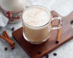 there is a cup of coffee on the table with cinnamons and milk in it