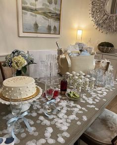 a table topped with a cake covered in frosting next to wine glasses and vases