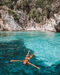 a person swimming in the water near some cliffs