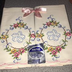 two white linens with pink bows and flowers on them, one has a label that says heritage