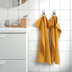 two yellow towels hanging on the wall next to a sink