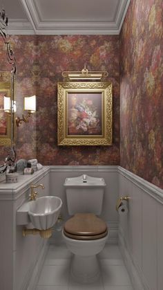 a bathroom with floral wallpaper and gold framed art on the wall above the toilet