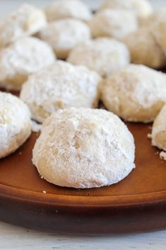 some powdered sugar cookies are on a wooden plate and ready to be eaten by someone