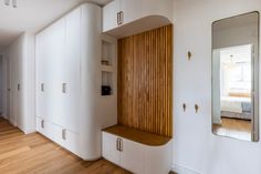 an empty room with white cabinets and wood accents on the wall, along with a large mirror