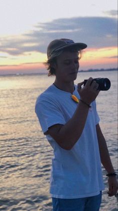 a man holding a camera near the ocean