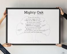 two people holding up a framed poster with the words mighty oak on it and an image of a tree