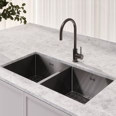 two black sinks sitting on top of a counter next to a potted green plant