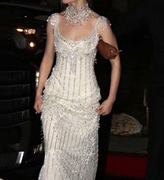 a woman in a white dress standing next to a car