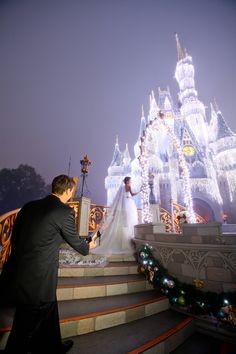 the bride and groom are getting ready to walk down the stairs in front of cinderella's castle