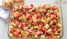 a casserole dish with strawberries and other fruit toppings in it next to a croissant