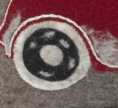 a close up of a red and white object with black circle on the center, surrounded by yarn