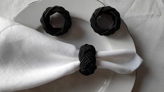 two black napkin rings sitting on top of a white plate