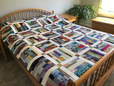 a bed with a quilt on top of it in a room next to a window