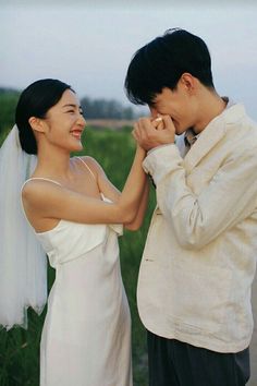 a man and woman standing next to each other in front of a green grass covered field