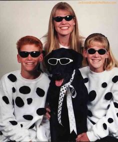 three people in matching sweaters and sunglasses pose with a dog