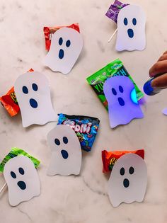 some candy bags with ghost faces on them are being held by someone's hand