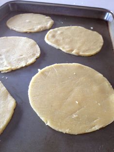 six uncooked pizza doughs on a baking sheet