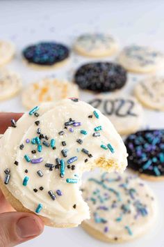 a hand holding up a frosted donut with sprinkles and the words, quick & easy new year's eve cookies