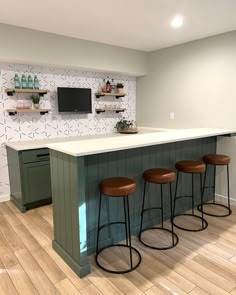 a kitchen island with three stools in front of it and a television on the wall