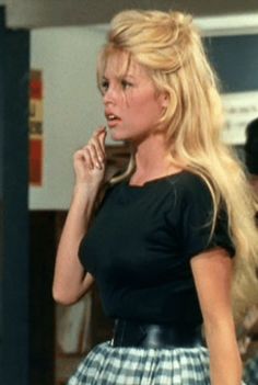 a woman with long blonde hair is talking on her cell phone while wearing a skirt