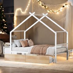 a bed with a white frame and wooden drawers underneath it in front of a christmas tree