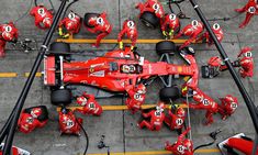 the ferrari car is surrounded by mechanics