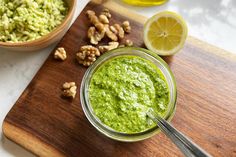 a jar filled with pesto and walnuts on top of a wooden cutting board