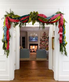 a living room decorated for christmas with red, green and blue ribbons hanging from the ceiling